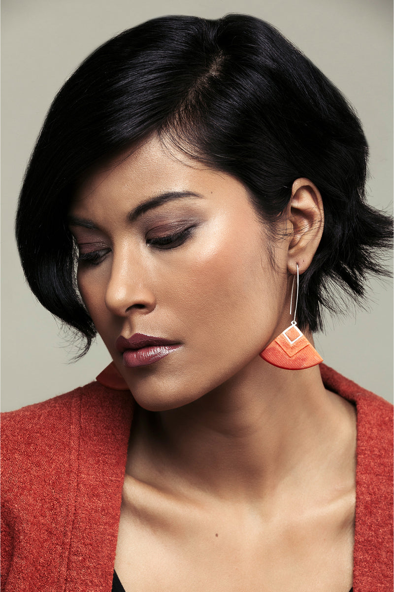 dark-haired model wearing Cléopâtre statement earrings, in coral red resin and hypoallergenic stainless steel