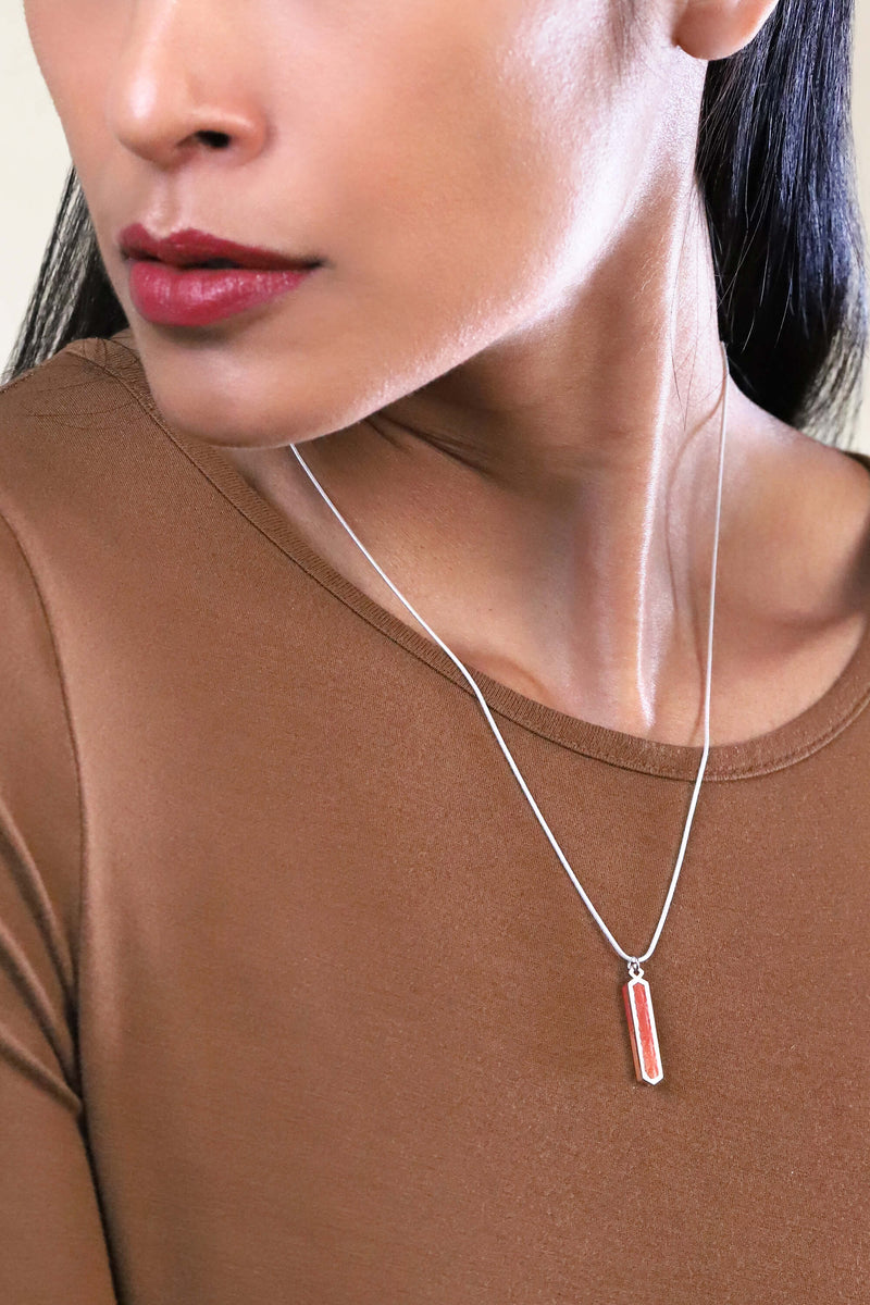 Modèle de mode féminine portant le collier Solstice à longueur réglable en résine durable de couleur rouge et chaîne en acier inoxydable hypoallergénique, fabriqué à la main.