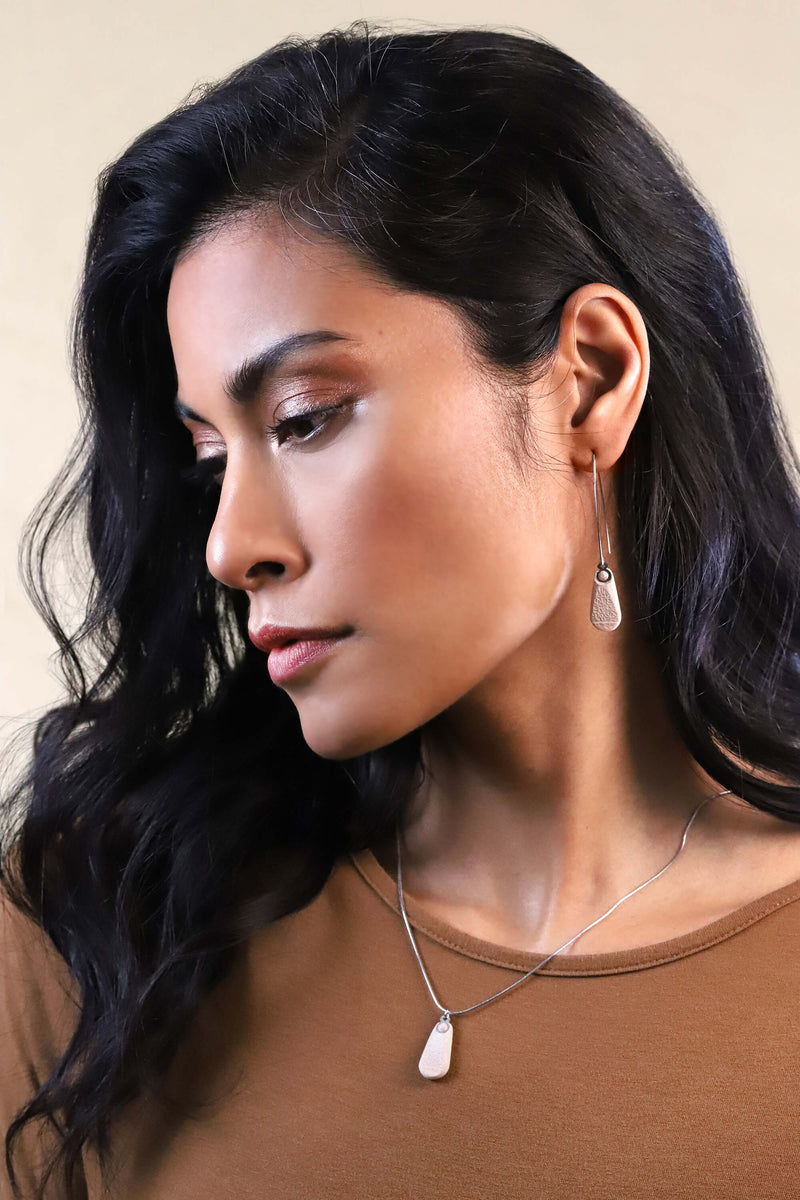 Modèle féminin de mode portant un collier à longueur réglable en résine durable et acier inoxydable hypoallergénique de couleur beige.