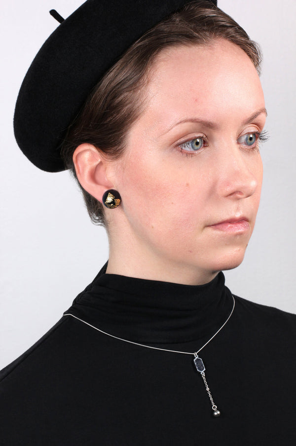 model wearing Astral color noir studs and 24 kt gold leaf spherical studs handmade in France, Dunkerque