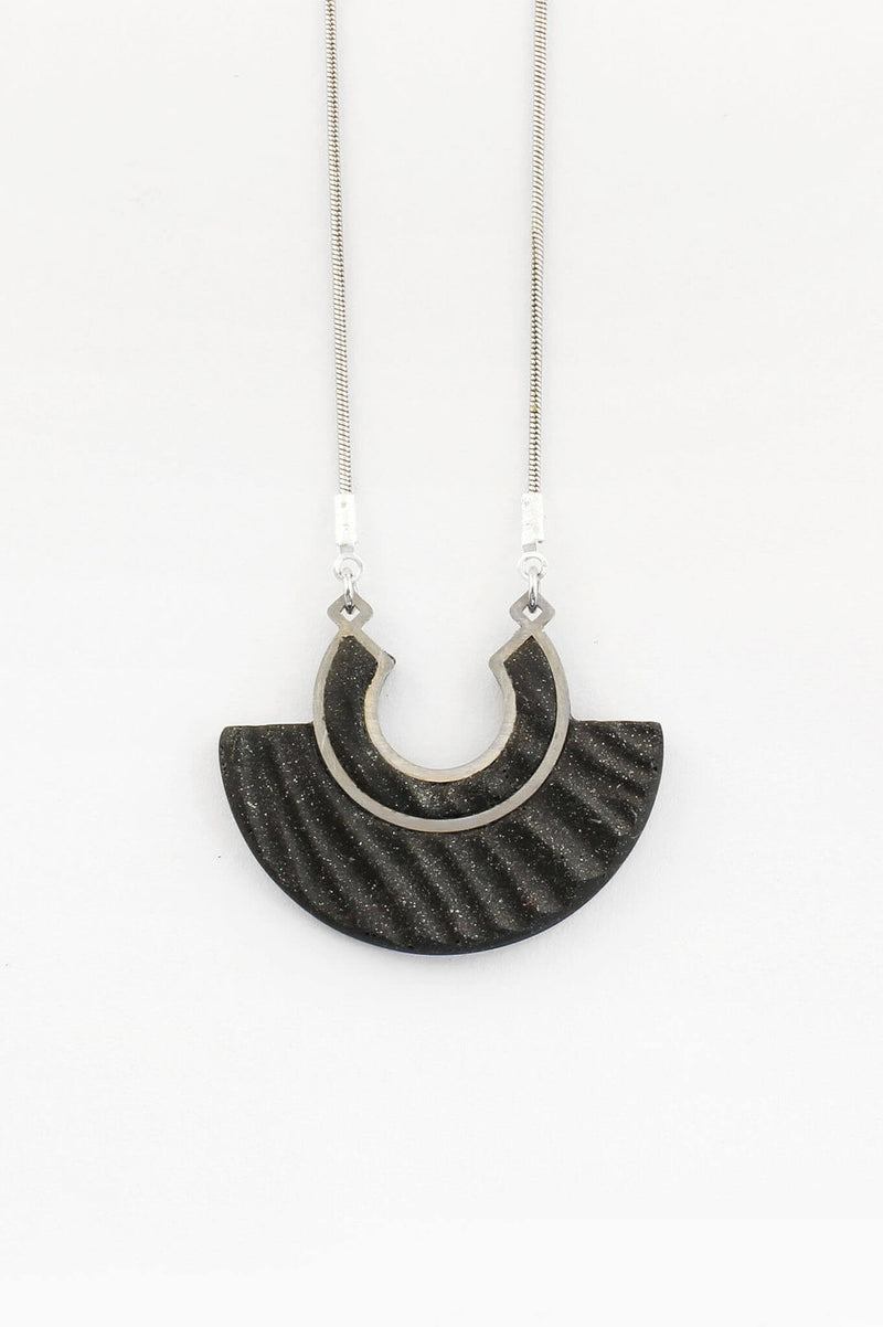 Le collier pendentif Aurore, en résine écologique de couleur noir et chaîne en acier inoxydable hypoallergénique, fabrication artisanale