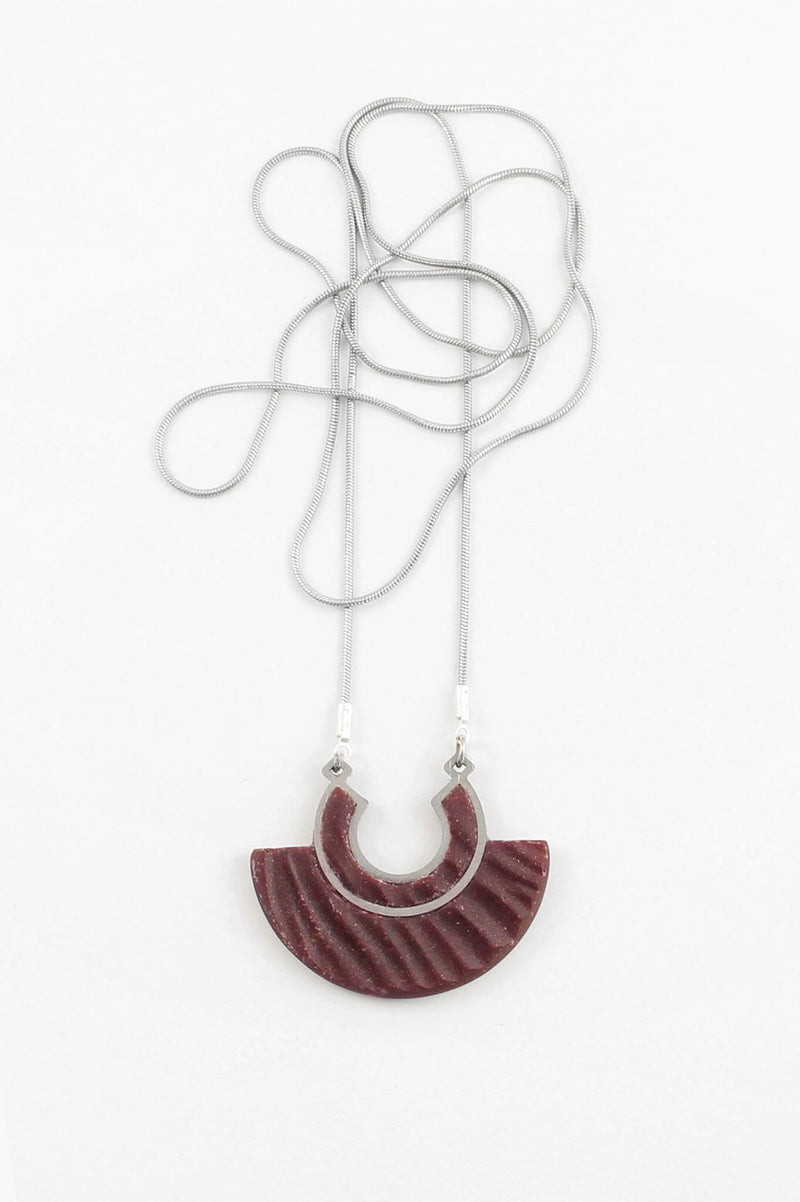 Le collier pendentif Aurore, en résine écologique de couleur bordeaux rouge foncé et chaîne en acier inoxydable hypoallergénique, fabrication artisanale