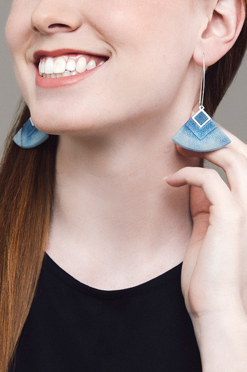 model wearing Cléopâtre statement earrings, in marbled indigo and pastel blue resin and hypoallergenic stainless steel