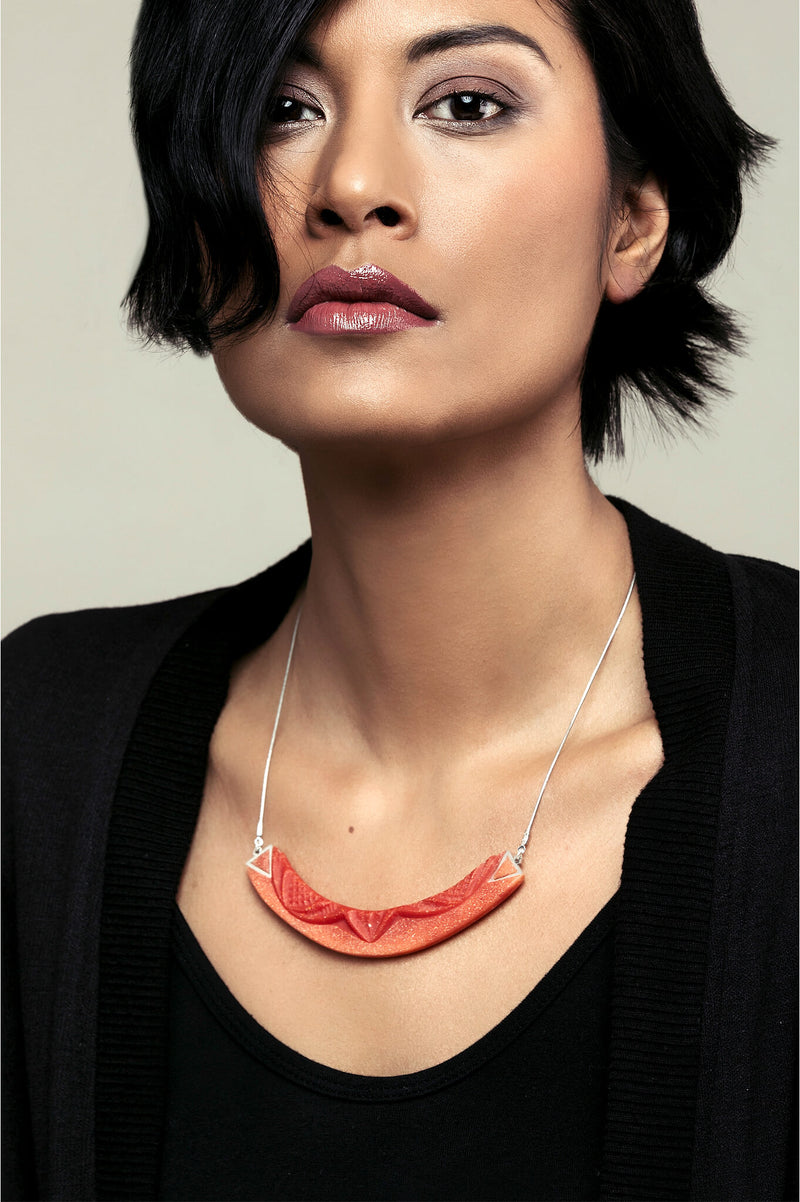 dark-haired model wearing Couronne, handmade necklace in coral red resin and hypoallergenic stainless steel