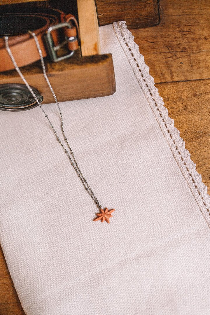 fashion flat lay of Etoile du Berger, coral red star-shaped necklace handmade in Montreal