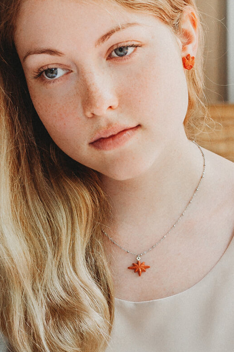 fashion model wearing matching coral red Lys studs and Etoile du Berger necklace