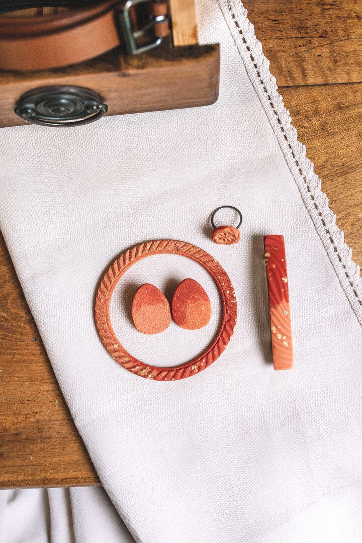 flat lay of designer Bijoux Pépine's handmade jewelry and hair accessories in coral red