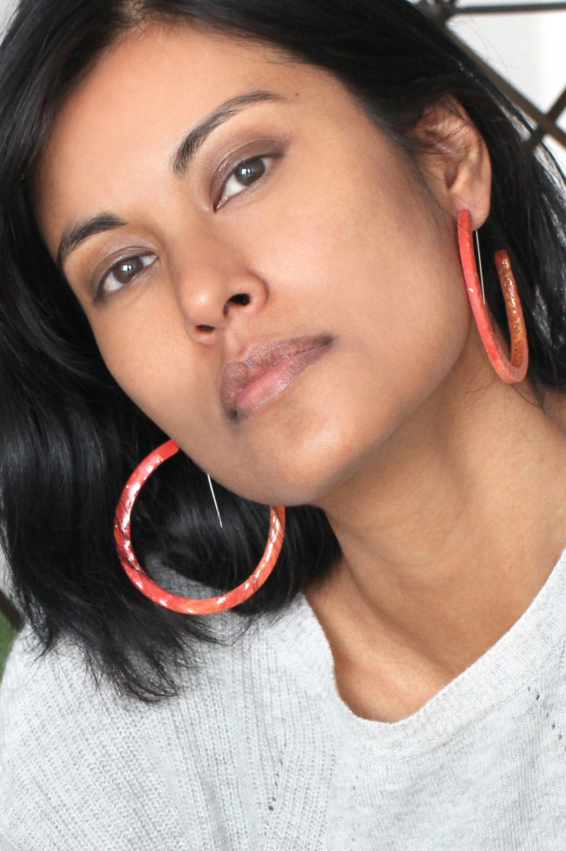 fashion model wearing Bijoux Pépine's handmade Ouroboros hoops in coral red