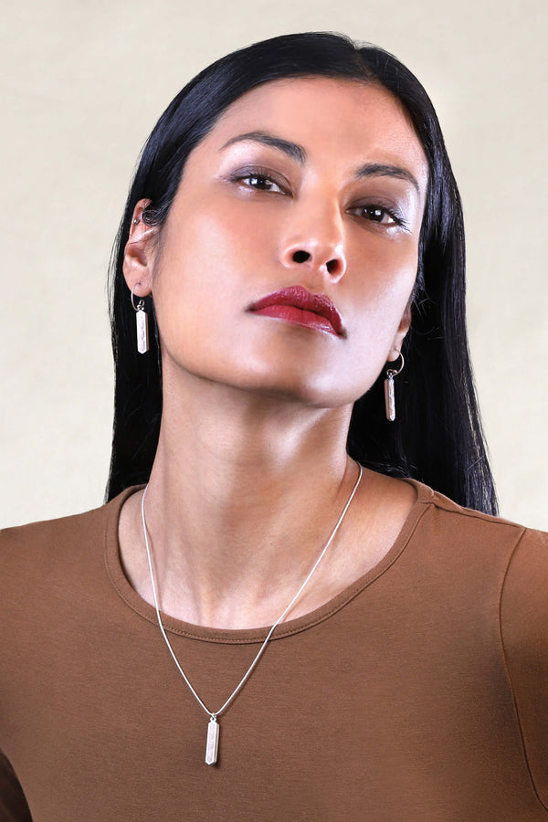 Beautiful woman wears Solstice jewellery set parure with earrings studs and teardrop adjustable length necklace in beige color resin and hypoallergenic stainless steel