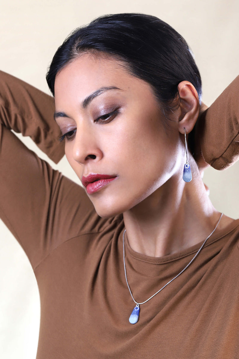 Fashion female model wearing Rosée teardrop shape earrings in indigo blue sustainable resin and long hypoallergenic stainless steel hooks