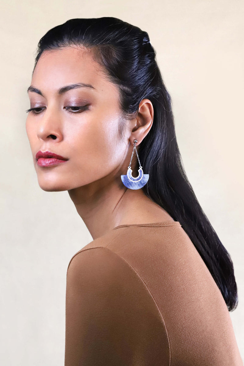 Beautiful model woman wears Aurora stud earrings, in sustainable resin of indigo blue color and hypoallergenic stainless steel chain, handmade