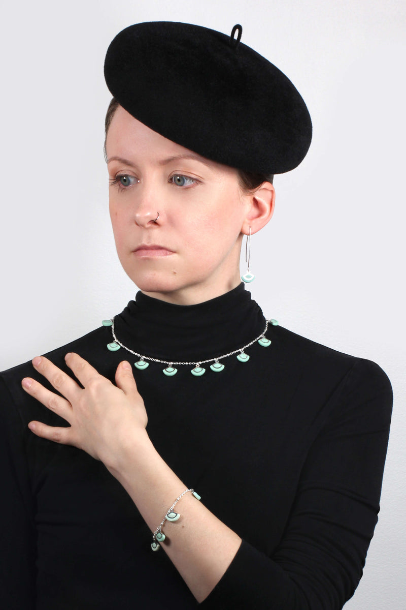 Modèle de mode féminine portant St-Jacques, boucles d'oreilles légères en forme de coquillage, fabriquées à la main avec de la résine durable de menthe verte et un crochet en acier inoxydable hypoallergénique.